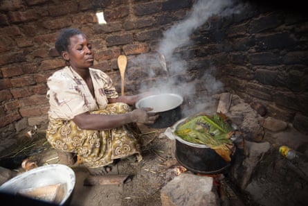 A woman cooks food over an open fire