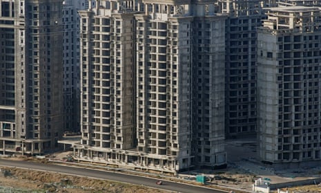 A vehicle travels passes unfinished tower blocks in Danzhou, Hainan province. The development by the Evergrande Group is subject to a demolition order.