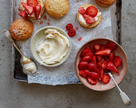 Strawberries, cream and cake laid out on a table.