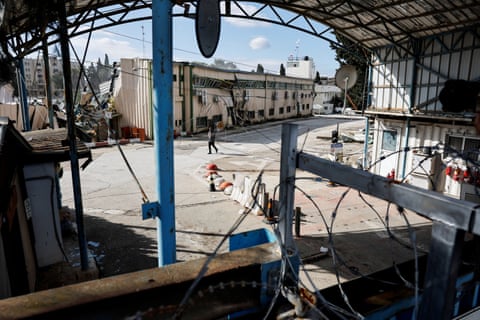 A man walks near fallen cables in a courtyard of damaged buildings.