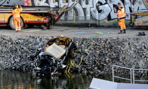 A badly damaged car is towed up from the canal under the E4 highway bridge in Sodertalje, Stockholm