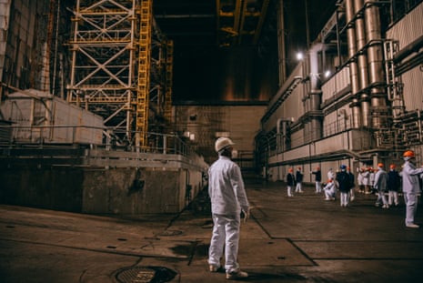 Workers in hard hats and overalls inside the huge safe confinement shelter