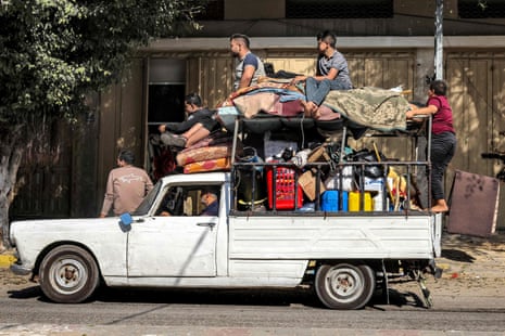 People ride with belongings in a vintage pickup truck as they evacuate their home in Rafah