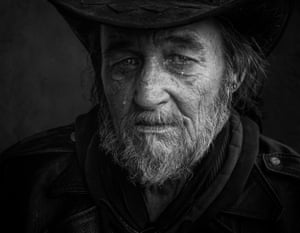 Close up of a older man with a beard in a black cowboy hate with tears in his eyes