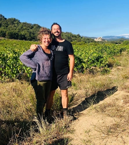 A man and a woman standing in front of a vineyard.