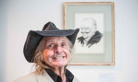 A man in a leather hat grins in front of a painting he created
