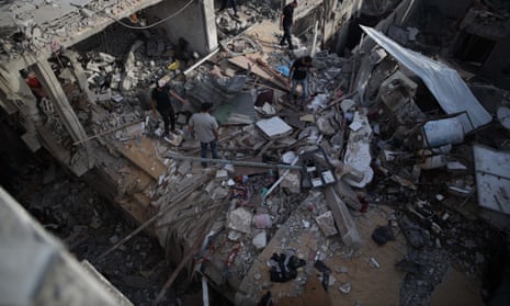 Pessoas inspecionam um prédio destruído no campo de refugiados de Nuseirat, no centro da Faixa de Gaza.