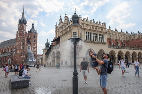 A man and child under a water sprinkler to cool off.