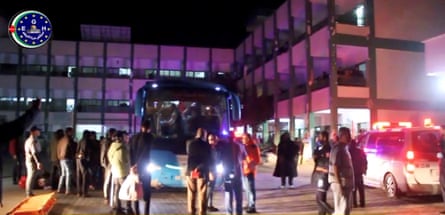 Bus and people outside hospital at night