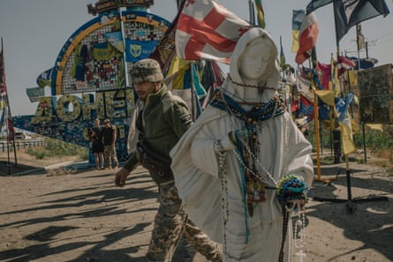 Soldiers and locals take photos at the monument marking the border of Ukraine’s eastern Donetsk oblast.