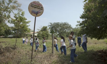 Children walk past a sign warning of the danger of hippos near the Hacienda Nápoles.
