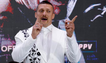 Oleksandr Usyk wearing a white suit and gesticulating
