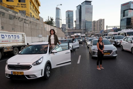 People stand next to their cars on the road.