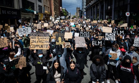 Protesters hold placards while marching down Deansgate Street during the demonstration.