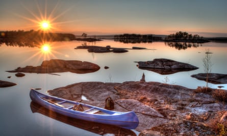 Sun low on the horizon in Sweden with a canoe in the foreground
