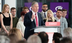 The Labour leader, Keir Starmer, speaks behind a lectern at a press conference, with several young people standing behind him