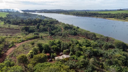 Pemandangan udara desa Ocoy, sekelompok kecil bangunan di antara pepohonan di sepanjang tepi sungai.