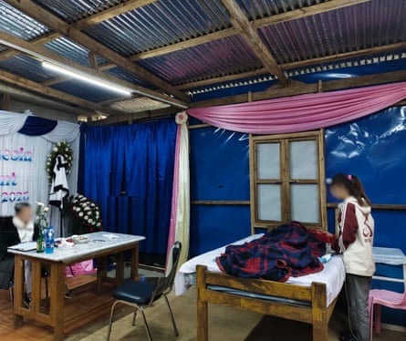 A young female stands astatine what looks for illustration a furniture pinch a broad connected it. Another female sits astatine a desk. A pinkish sash hangs connected 1 wall.