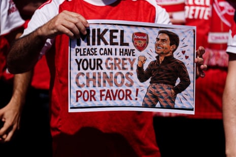 An Arsenal fan holding a sign featuring manager Mikel Arteta