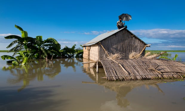A man sits on the roof of his hut after severe Flooding