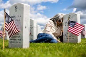 Woman leans against headstone in a military cemetery