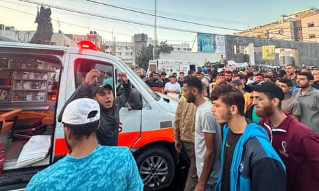 People gather around an ambulance hit in the airstrike near the al-Shifa hospital in Gaza City