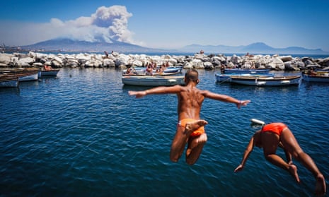 Children jump into the sea as smoke billows from fires around Mount Vesuvius in Naples, Italy