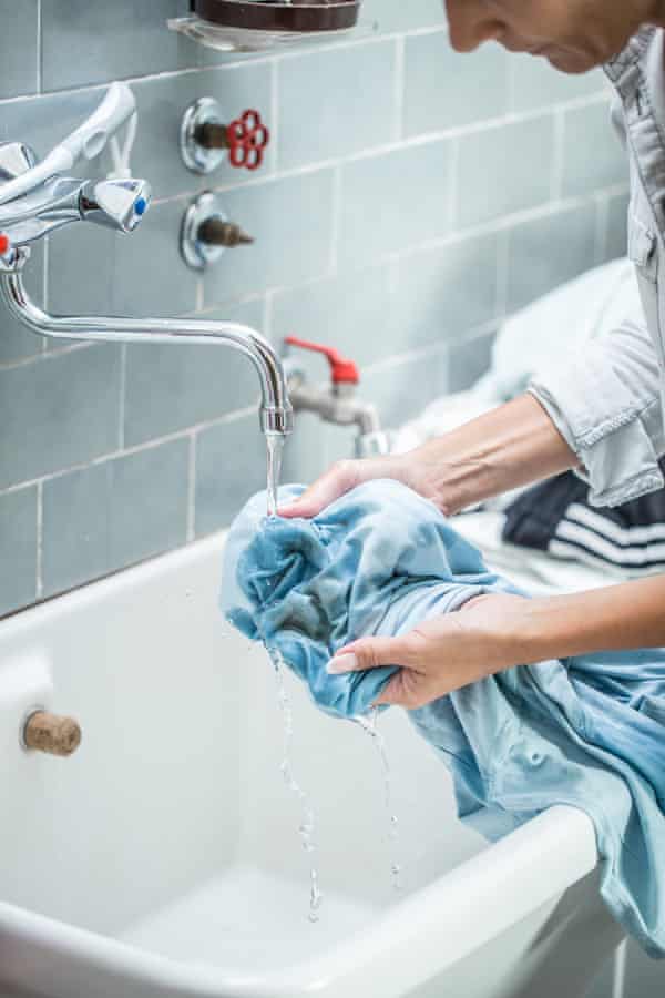 A person partially hand washing a blue blouse