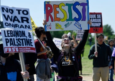a person holds a sign that reads ‘resist’
