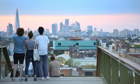 Young people view the City of London skyline at dusk