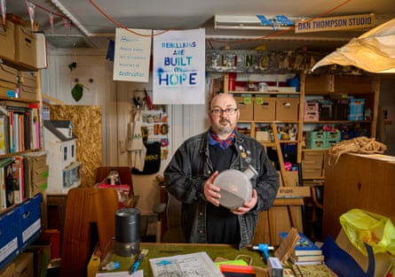 Middle aged man in an art studio surrounded by materials and boxes
