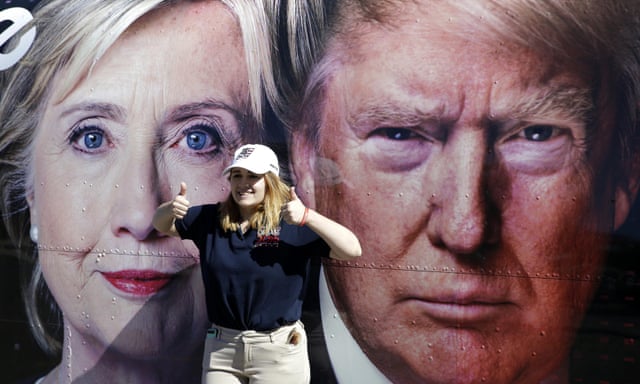 A young woman stands between a photo on a news truck of Donald Trump And Hillary Clinton on the eve of the first presidential debate at Hofstra University in Hempstead, New York.