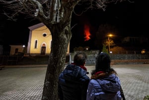 People watch lava flowing from the southern crater of the Etna volcano as a new eruptive episode of tall lava fountains, known as paroxysm, occurs.