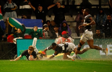 Damian McKenzie slides over with water splashing in the air to score a try for New Zealand