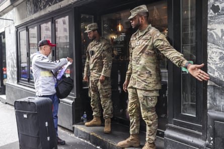 An asylum-seeker shows his documents to two US Army soldiers at the entrance of Roosevelt Hotel