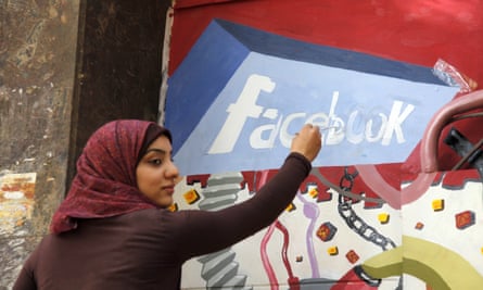 A student in Cairo paints the Facebook logo on a mural