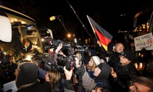 Media and demonstrators stand next to a bus carrying refugees from the Bavarian town of Landshut to Berlin
on Thursday.