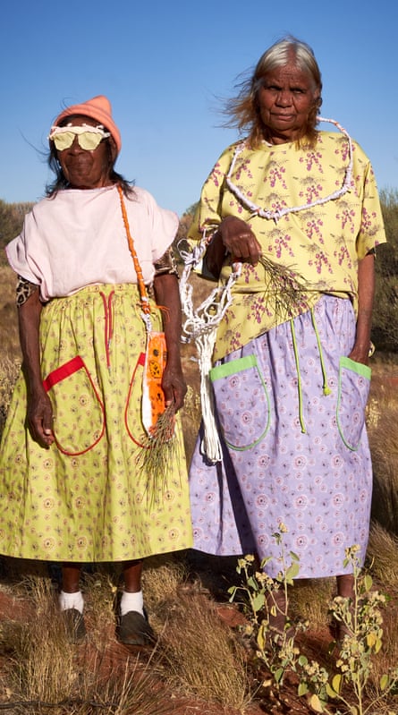 Dua wanita berdiri di padang pasir mengenakan rok dan blus bermotif gemerlap