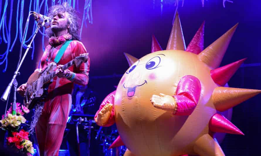 A huge spiky balloon with a happy face joins Coyne on stage