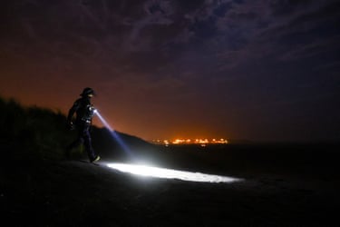A police officer patrols the beach with a torch
