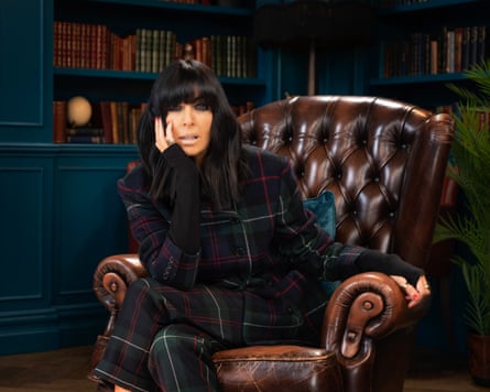 Claudia Winkleman sits in a leather arm chair on the set of The Traitors.