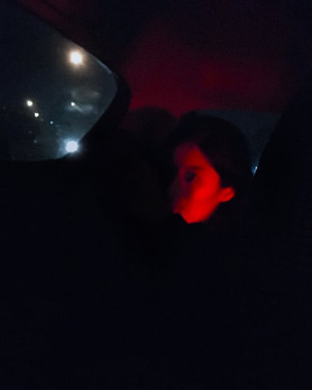 Grainy and unclear image of part of a girl’s face bathed in red light, with what could be a riot shield very close to her.
