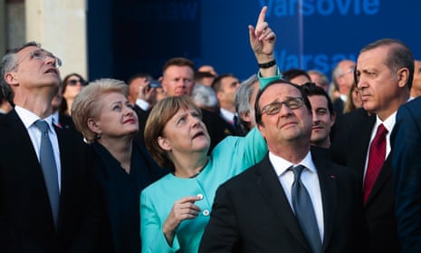 Germany’s Chancellor Angela Merkel points at the sky during a fly-past in Warsaw