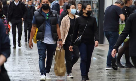 People walk along Oxford Street while wearing face masks.