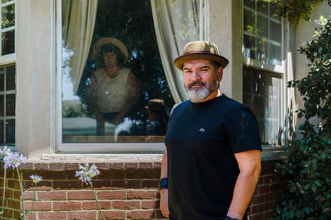 Man in porkpie hat stands outside window, where young woman stands in shadow.