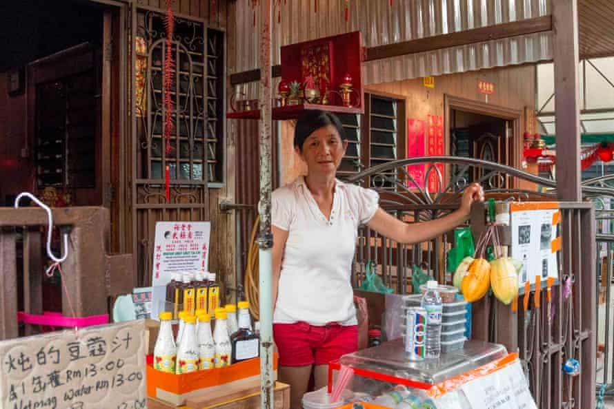 A resident of the Chew Jetty sells snacks to tourists outside her historic stilt home. Her floating village was inundated by tourists after George Town, Malaysia was dubbed a UNESCO World Heritage site in 2008.