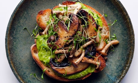 Two slices of toast side by side and piled with mushrooms and sprinkled with little sprouts