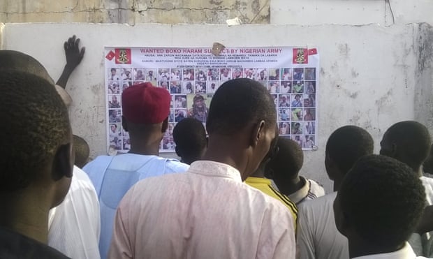 People gather to inspect a wanted poster of Boko Haram suspects in Maiduguri, Nigeria.