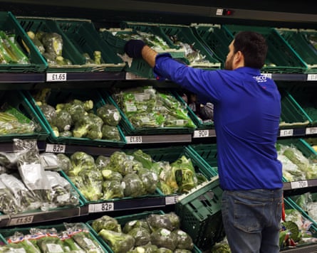 A Tesco worker stacking shelves of vegetables