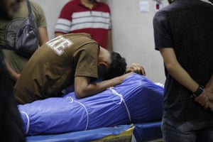 A young man weeps over a shrouded body